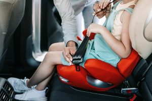 adult buckling child into car safety seat